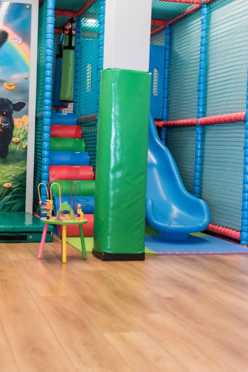 Indoor play area with a slide and padded climbing structure at Prime Wagyu