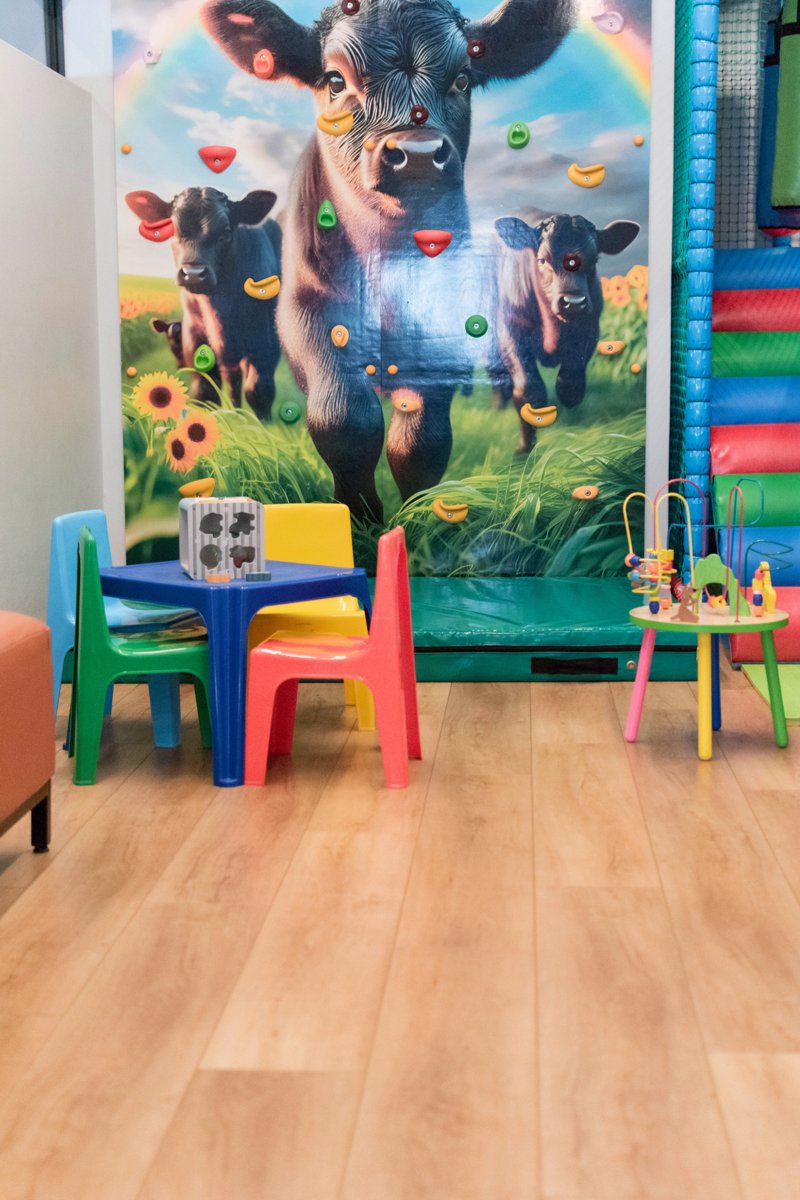 Children’s table, chairs and activity toys beside the cow mural in the playroom