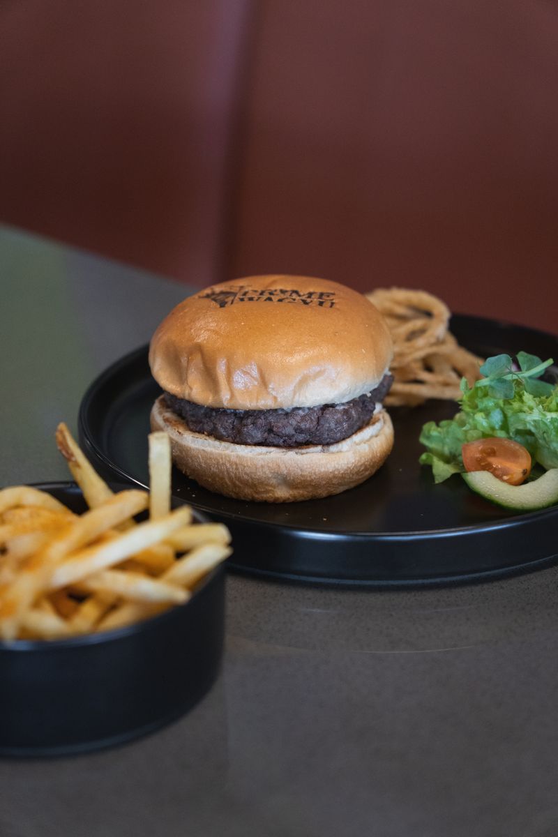 A Prime Wagyu burger with a branded bun, onion rings and fries